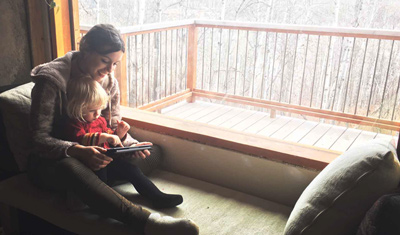 Alex playing with her host child on the tablet. 