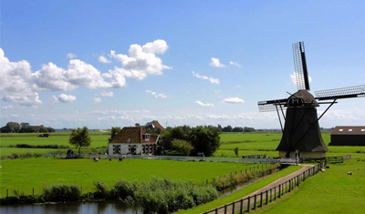 Idyllisch Holland: windmolen, blauwe hemel, groen gras en wolken