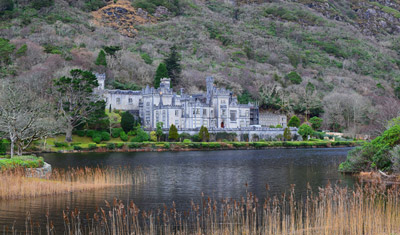 A castle situated besides a river, at the foot of a hill, somewhere in Ireland.