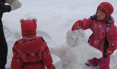 Tiinas's children are building a snowman with their Spanish au pair.