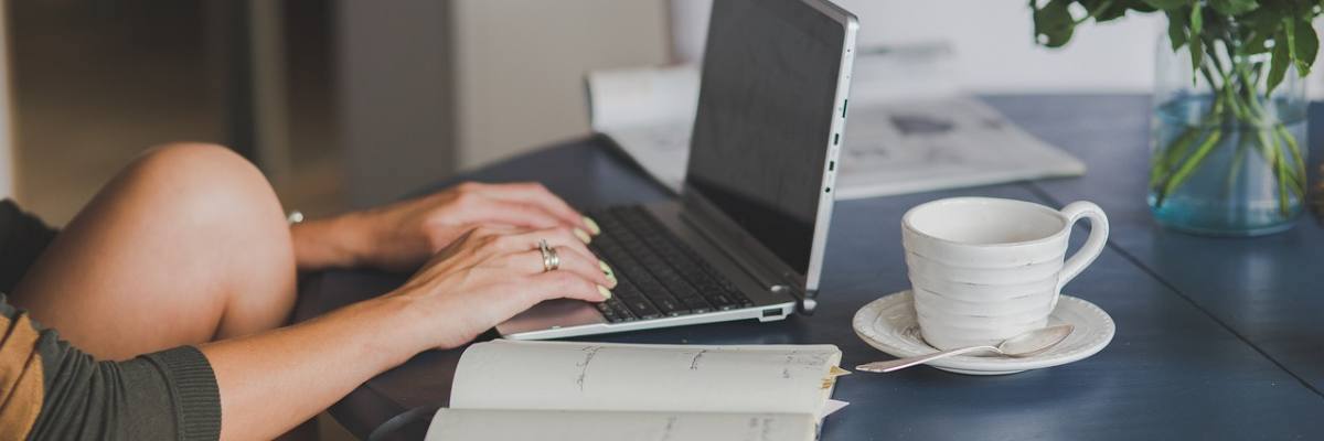 Girl sitting at the table, writing on her laptop
