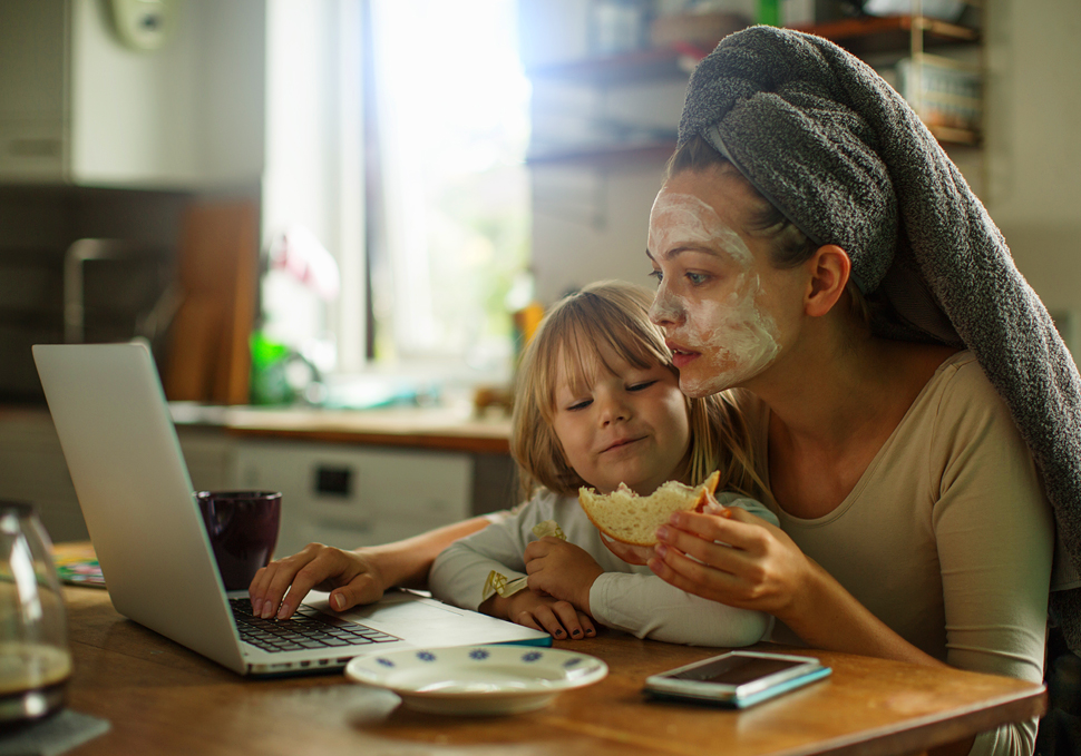 Una mamma al computer con in braccio sua figlia