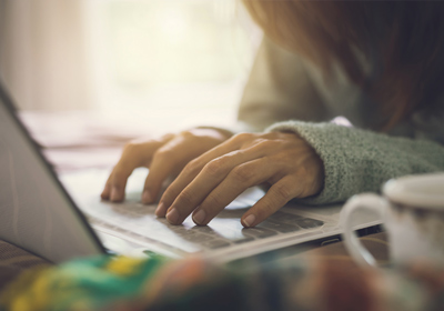 Young woman typing on a laptop and registering as an au pair