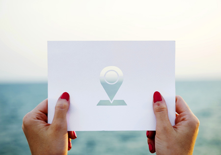 Woman's hands holding card with location icon