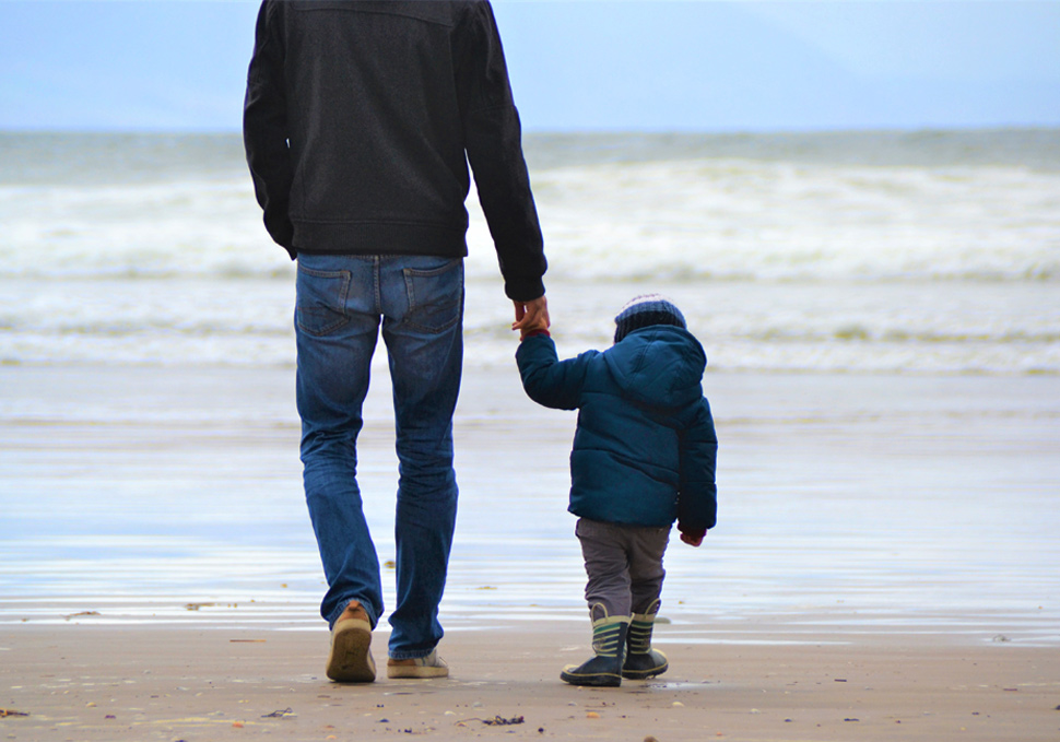 Mann and child hand in hand on the beach