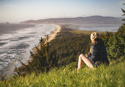 Travelling young woman looking at a bay