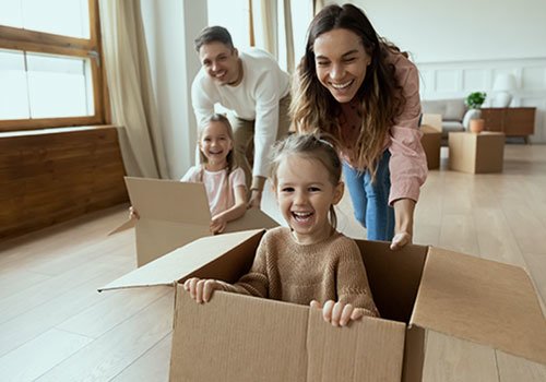 Parents play with cardboard moving boxes with their kids